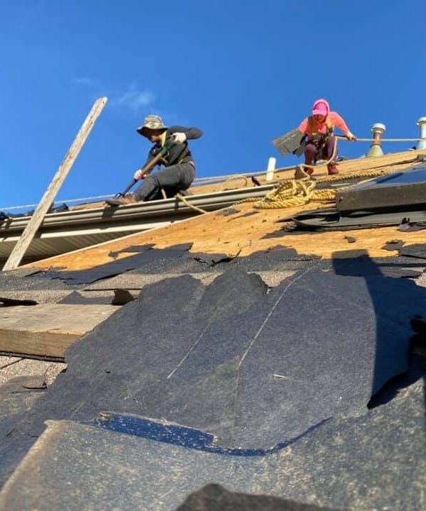Workers on roof repairing shingles