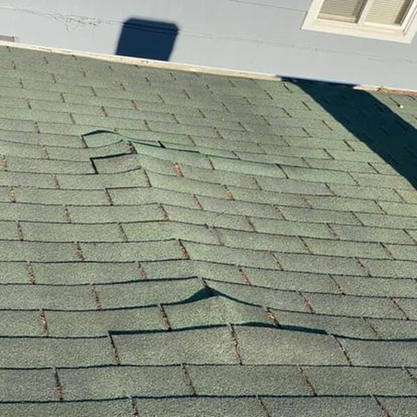 Damaged shingles on roof of home after a storm