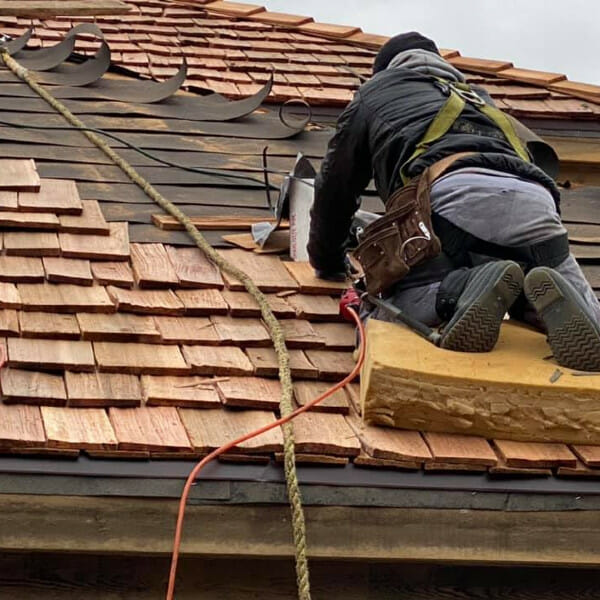 Man working on a wooden shingle roof replacement